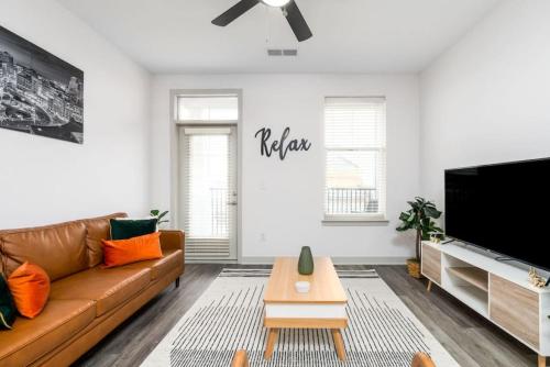 a living room with a brown couch and a flat screen tv at Affordable 2-Bedroom Whitestown in Whitestown