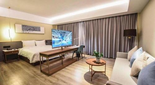 a hotel room with a bed and a desk with a television at AURAYA BY SUNING NANJING XUZHUANG in Nanjing