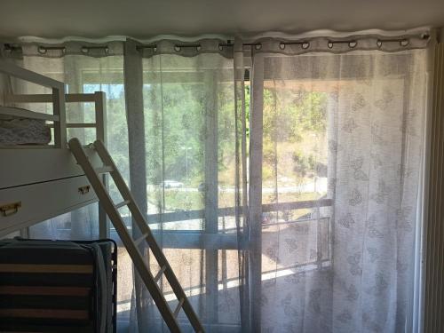 a window with curtains and a ladder next to a bed at Studio Villard-de-Lans in Villard-de-Lans