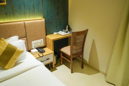 a bedroom with a bed and a chair and a desk at Hotel Skylink Hospitality Mahalaxmi in Mumbai