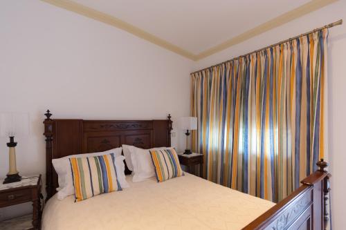 a bedroom with a bed with a wooden headboard and curtains at Casa de São Domingos in Peso da Régua