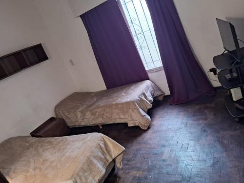 2 Betten in einem Zimmer mit Fenster und lila Vorhängen in der Unterkunft casa en escobar con cocheras in Belén de Escobar