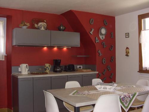 cocina con mesa y pared roja en Gîte Labaroche Temps Libre, en Labaroche