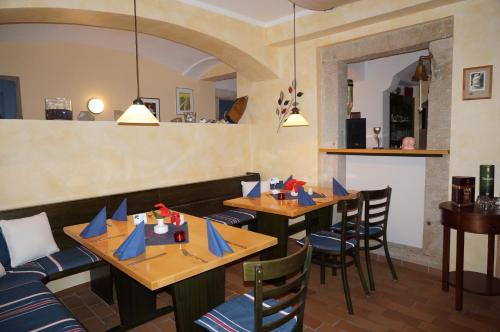 ein Restaurant mit Holztischen und Stühlen mit blauen Servietten in der Unterkunft Pension Goldener Anker in Reinhardtsdorf