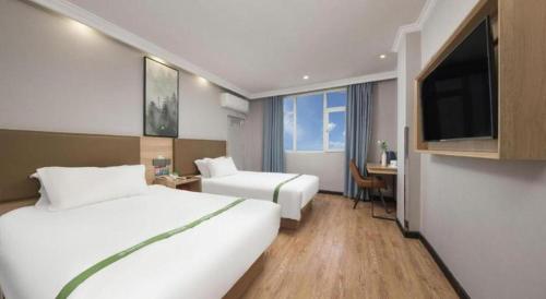 a hotel room with two beds and a flat screen tv at GreenTree Inn Jiaxing Tongxiang Tudian Express Hotel in Jiaxing