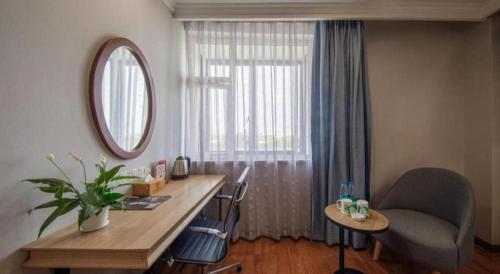 a living room with a desk and a window at GreenTree Inn Jiaxing Tongxiang Tudian Express Hotel in Jiaxing