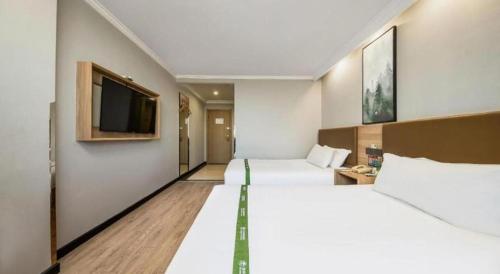 a hotel room with two beds and a flat screen tv at GreenTree Inn Jiaxing Tongxiang Tudian Express Hotel in Jiaxing