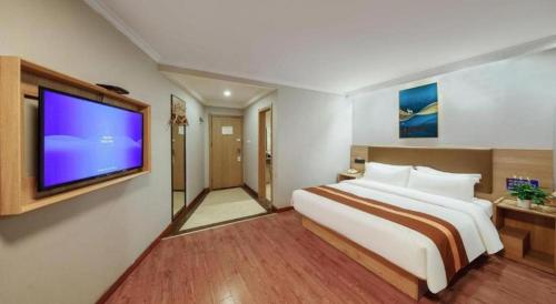 a bedroom with a large bed and a flat screen tv at GreenTree Inn Jiaxing Tongxiang Tudian Express Hotel in Jiaxing