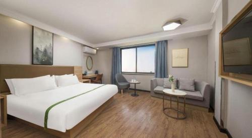 a hotel room with a large bed and a couch at GreenTree Inn Jiaxing Tongxiang Tudian Express Hotel in Jiaxing
