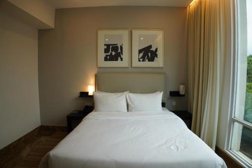 a bedroom with a white bed and a window at Empyrean Dhaka City Centre in Dhaka