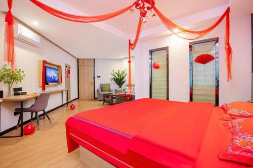 a bedroom with a red bed and a desk with a computer at GreenTree Inn Puyang Pushang Huanghe Road in Puyang