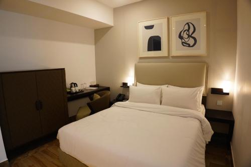 a bedroom with a large white bed and a desk at Empyrean Dhaka City Centre in Dhaka