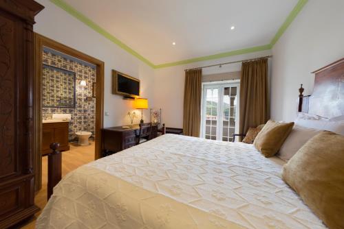 a bedroom with a large bed and a bathroom at Casa de São Domingos in Peso da Régua