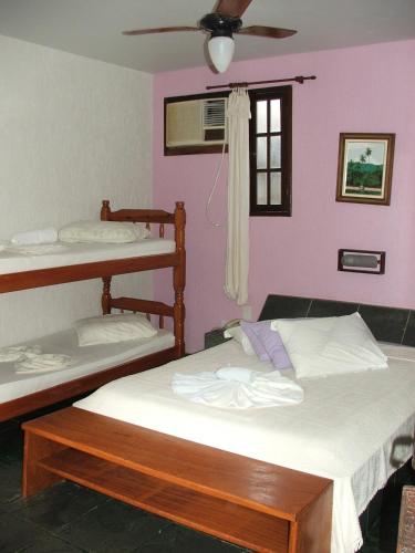 two beds in a room with pink walls at Pousada Caúca in Abraão