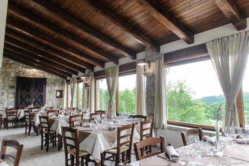 uma sala de jantar com mesas e cadeiras e janelas grandes em Domus Otium em Atena Lucana