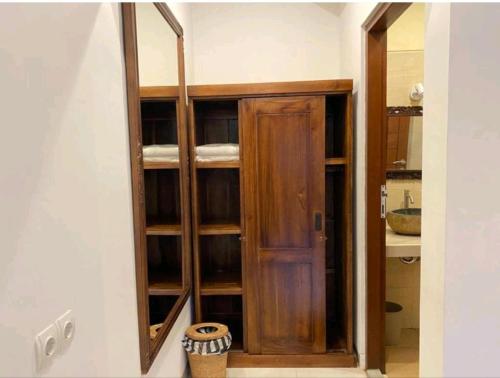 a wooden cabinet with a mirror in a room at Villa Popolan and Guest House in Ubud