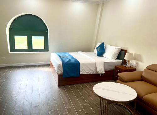 a bedroom with a bed and a couch and a window at Royal Louis Hotel in Hanoi