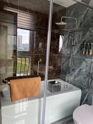 a bathroom with a tub and a glass shower at Royal Louis Hotel in Hanoi