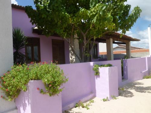 uma cerca roxa em frente a uma casa com flores em Casa Grande em Galinhos