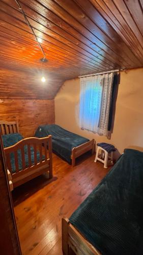 a room with two beds and a wooden ceiling at MOUNTAIN HOUSE In ROSHKA in Roshka