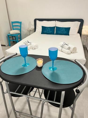 un tavolo con due bicchieri blu sopra accanto a un letto di Cisternone Suites a Formia