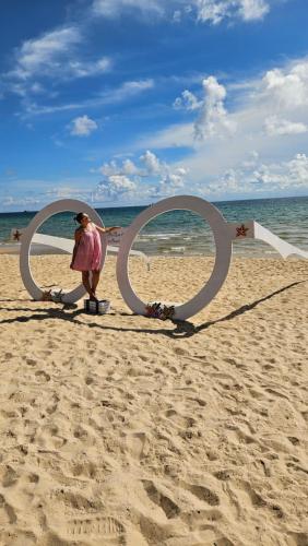 a woman standing on the beach in front of two o rings at ADRI Hotel in Phu Quoc