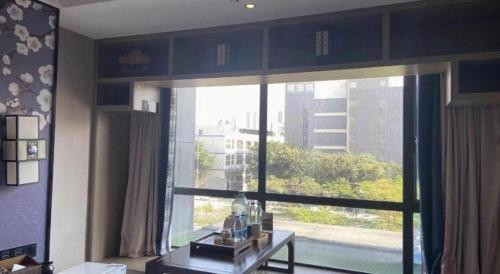 a living room with a large window with a view at Yuan Culture Hotel Shenzhen World Shajing in Shenzhen