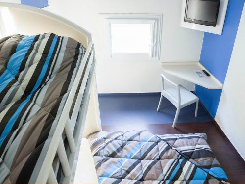 Saint-NabordにあるhotelF1 Remiremont Saint Nabordの二段ベッド1組、デスクが備わる小さな客室です。