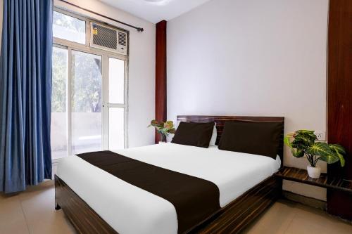 a bedroom with a bed and a large window at SPOT ON Jahanvi Guest House in Neral