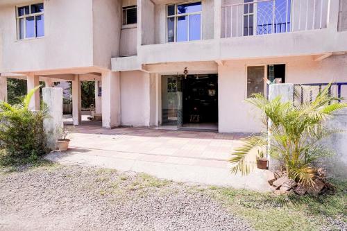 a building with a door and a palm tree at SPOT ON Jahanvi Guest House in Neral