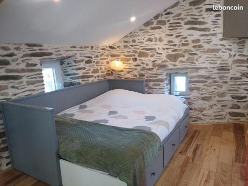 un lit dans une chambre avec un mur en pierre dans l'établissement Gîte,bergerie en moyenne montagne, à Lacaze