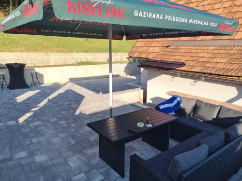 a patio with a couch and an umbrella at Vikendica Artos in Bihać
