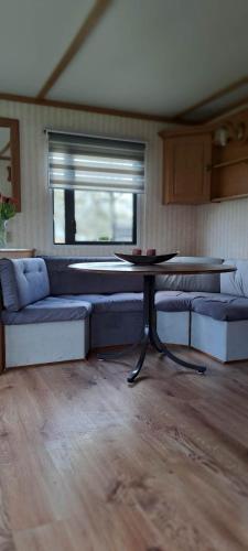 a living room with a table and couches and a window at Leśna Aura in Ponizie