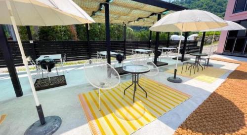 a patio with tables and chairs and umbrellas at All That Water Pension in Gapyeong