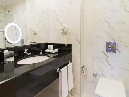 een badkamer met een wastafel, een spiegel en een toilet bij Metropolitan Hotels Ankara in Ankara