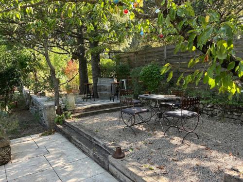 un patio avec une table et des chaises sous un arbre dans l'établissement Maison en Drôme Provençale, à Montségur-sur-Lauzon