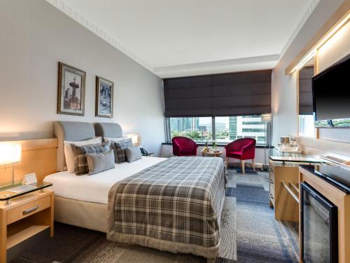 um quarto de hotel com uma cama e uma televisão em Metropolitan Hotels Ankara em Ancara