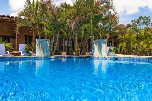 a large blue swimming pool with palm trees in the background at Casa Lajagua in Pedasí Town