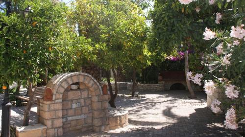 a stone oven in a garden with trees and flowers at Villa Christina in Tolo