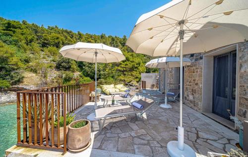 a patio with two umbrellas and chairs and water at 4 Bedroom Gorgeous Home In Korcula in Korčula