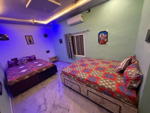 a bedroom with two beds and purple lights at Roshini Homestay Hampi in Hampi