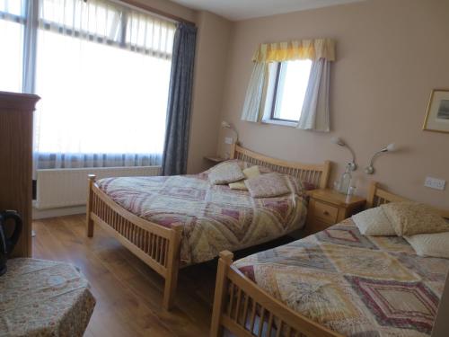 a bedroom with two beds and two windows at The Stone House B&B in Baltimore