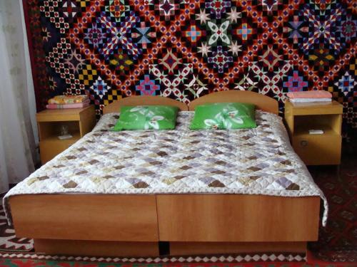 a bedroom with a bed with green pillows at Guest House Nur in Kochkorka