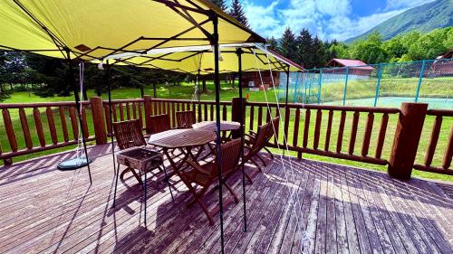 a table and chairs under a yellow umbrella on a deck at Villa Rusutsu in Rusutsu