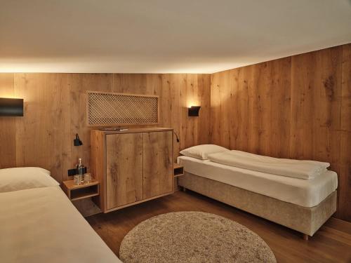 two beds in a room with wooden walls at DAS EDELWEISS - Salzburg Mountain Resort in Grossarl
