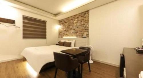 a bedroom with a bed and a table and chairs at H Hotel in Ulsan