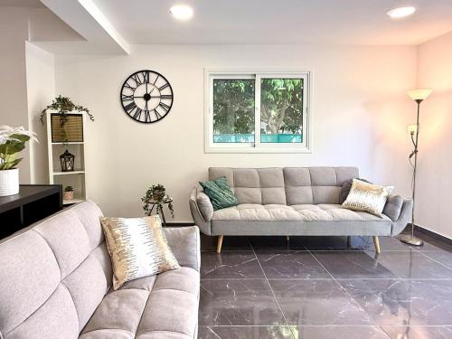 a living room with a couch and a clock on the wall at Elegant Beach Villa Moonstone II in Meneou