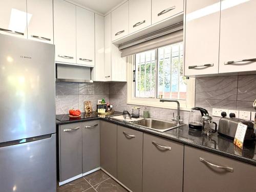 a kitchen with white cabinets and a stainless steel refrigerator at Elegant Beach Villa Moonstone II in Meneou