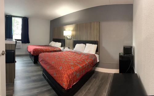 a hotel room with two beds with red sheets at Blue Way Inn and Suites Roseville in Roseville