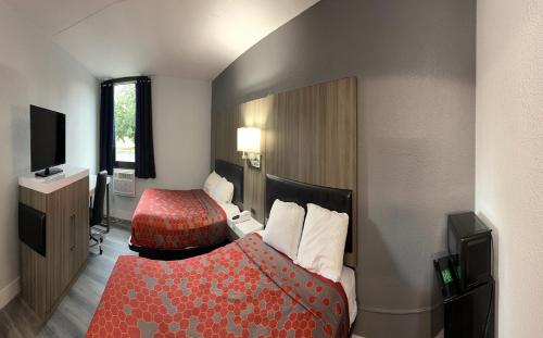a hotel room with a bed and a television at Blue Way Inn and Suites Roseville in Roseville
